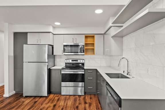 A modern kitchen with a refrigerator, oven, and microwave.