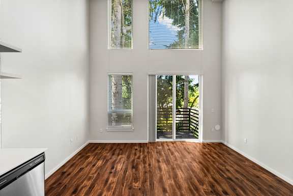 A room with a wooden floor and a large window with blinds.