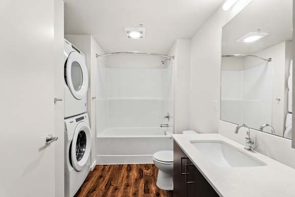 A white bathroom with a washer and dryer built in.