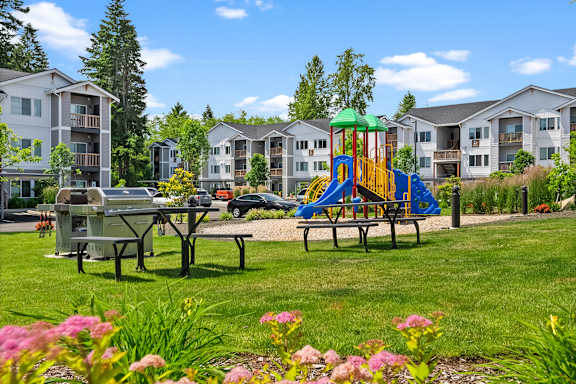 A playground with a slide and a picnic table in the foreground.