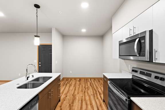 A modern kitchen with wooden floors and stainless steel appliances.