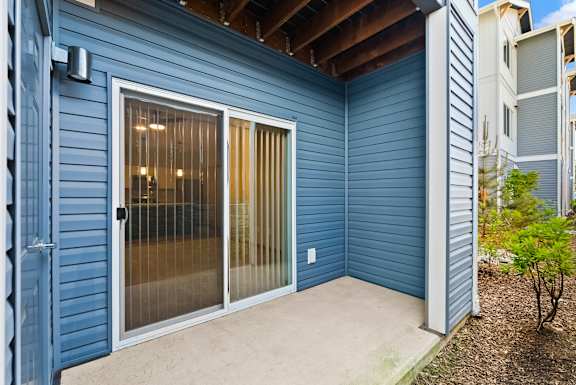 A blue house with a glass door and a brown roof.