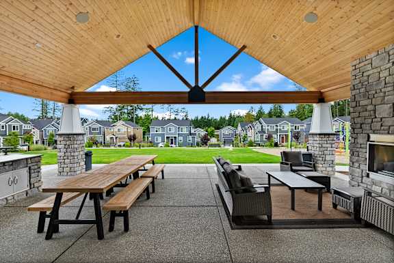 A wooden picnic table is in the middle of a patio.