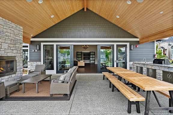 A patio with a stone fireplace and a wooden table.