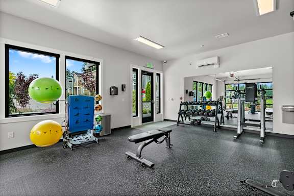 A gym with a variety of equipment including a bench, weights, and a squat rack.