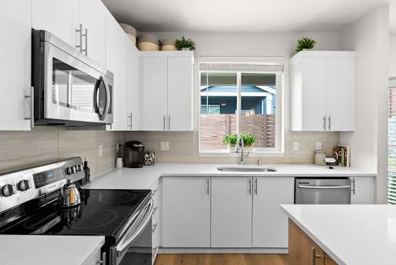 A modern kitchen with white cabinets and a black stove top.