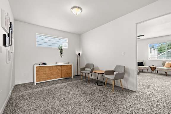 A room with a grey carpet and a wooden cabinet.