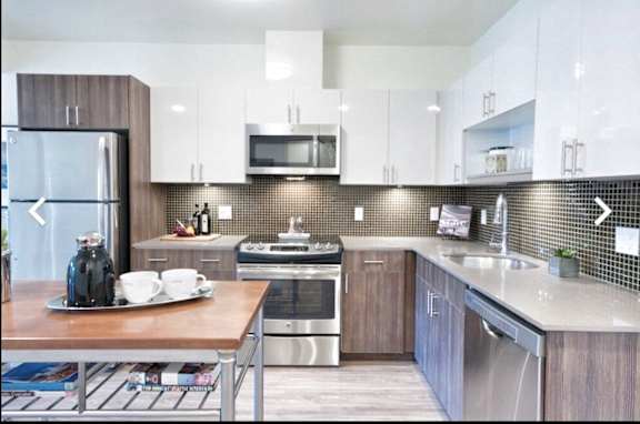 A modern kitchen with a wooden table, backsplashes, and stainless steel appliances.