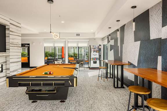 A pool table is in the middle of a room with a black and white wall.