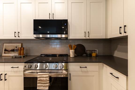 A modern kitchen with white cabinets and a black stove top.