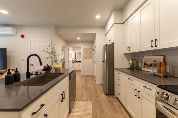 A modern kitchen with white cabinets and black countertops.
