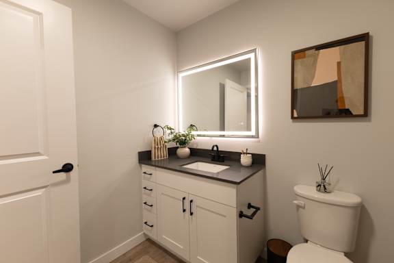 A bathroom with a white toilet and a mirror above a sink.