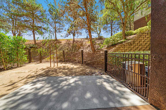 A driveway with a gate and trees on either side.