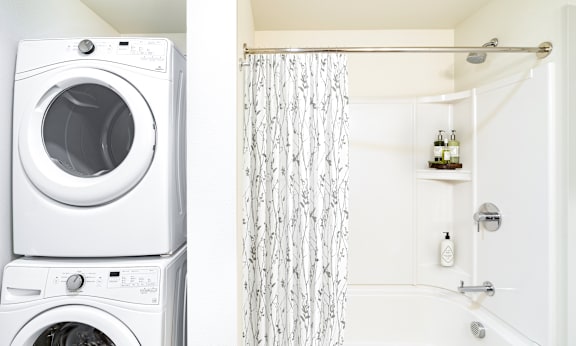 A white washing machine and dryer stacked on top of each other in a laundry room.