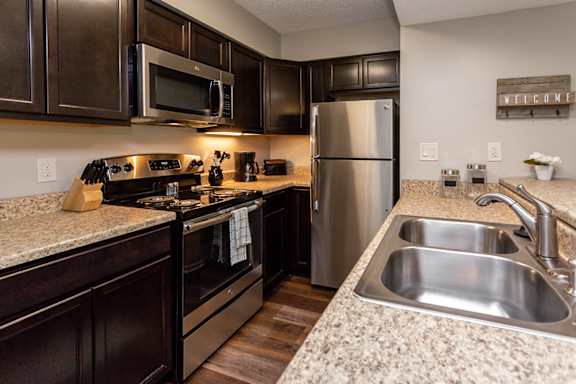 A kitchen with dark brown cabinets and stainless steel appliances.