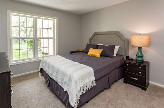 A bedroom with a bed, nightstand, and window.