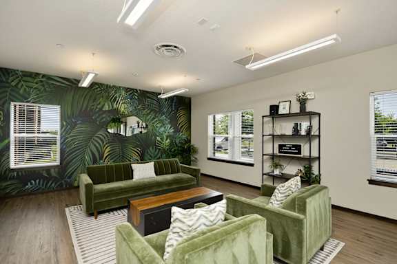 A living room with green couches and a leafy wallpaper.