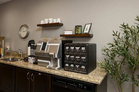 A black coffee machine with a digital display is on a granite countertop.