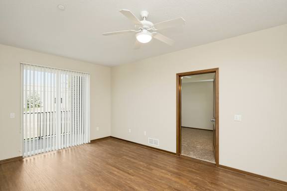 A room with a ceiling fan and a door leading to a hallway.