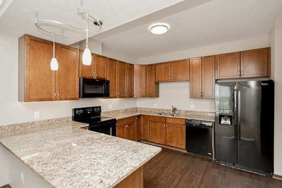 A kitchen with granite countertops and wooden cabinets.