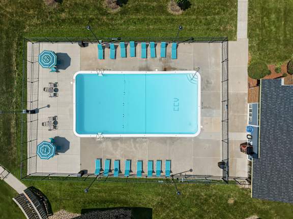 An aerial view of a swimming pool with lounge chairs and umbrellas.