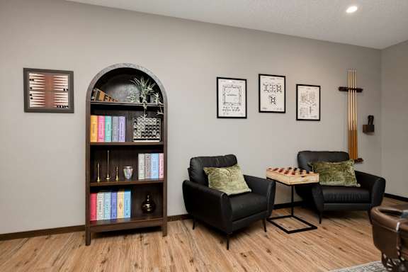 A living room with a bookshelf, two chairs, and a table.