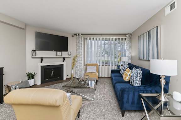 A living room with a blue couch and a fireplace.