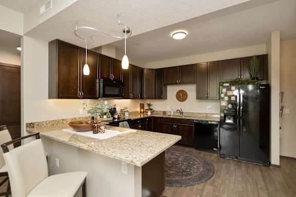 A kitchen with a granite countertop and a black refrigerator.