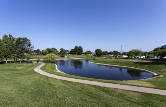 A pond in a park with a clear blue sky.
