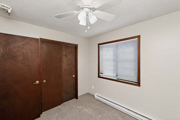 A room with a ceiling fan and a window with blinds.