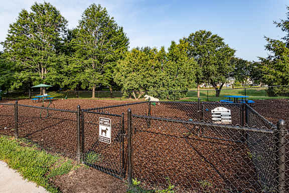 A dog park with a fence and a sign on it.