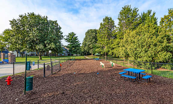 A playground with a red slide and a blue picnic table.