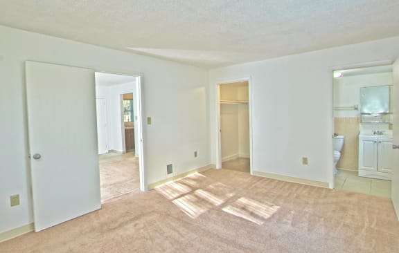 an empty living room with a rug and a bathroom
