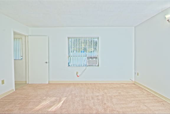 an empty living room with a heater on the wall