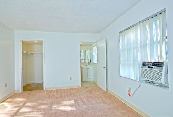 a living room with an air conditioner on the wall and a door to a
