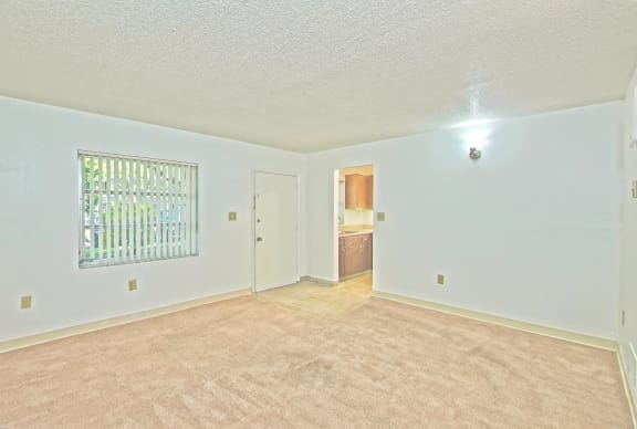 an empty living room with a window and a door to a bathroom
