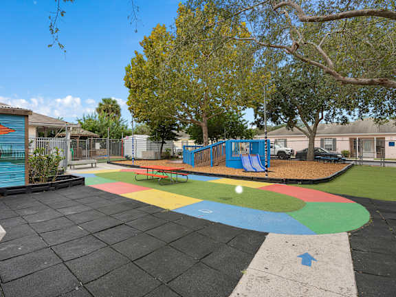 a playground with a multicolored circle in the middle of it and some trees