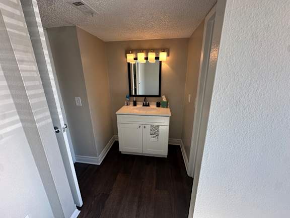 A white bathroom vanity with a mirror and lights above it.at Auburn Glen Apartments, Jacksonville
