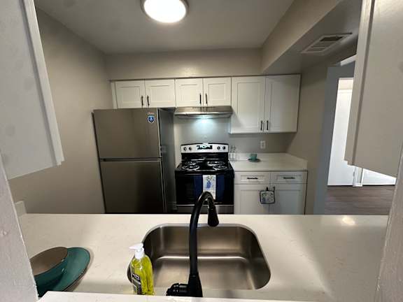 A kitchen with a stainless steel sink and a black vacuum cleaner.at Auburn Glen Apartments, Jacksonville