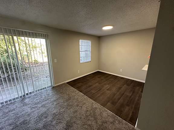 A room with a sliding glass door and a window with blinds.at Auburn Glen Apartments, Jacksonville