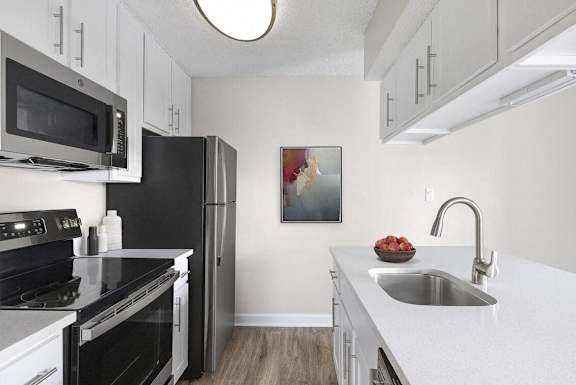 A kitchen with black appliances and white cabinets.