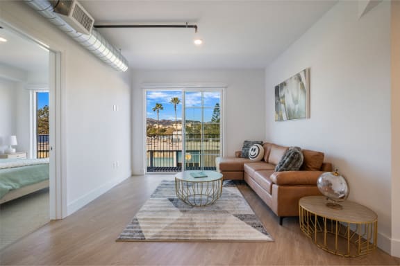 a living room with a couch and a coffee table and a door to a balcony