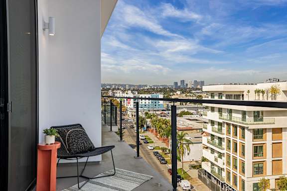 A balcony with a chair and table overlooks a city street.at WM by CLG, Los Angeles