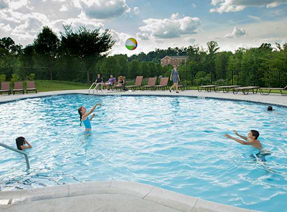 People playing in a blue pool with a ball in the air.