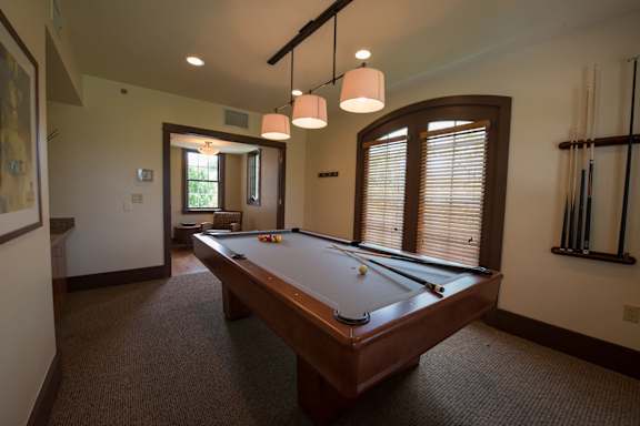 A pool table in a room with a brown carpet.