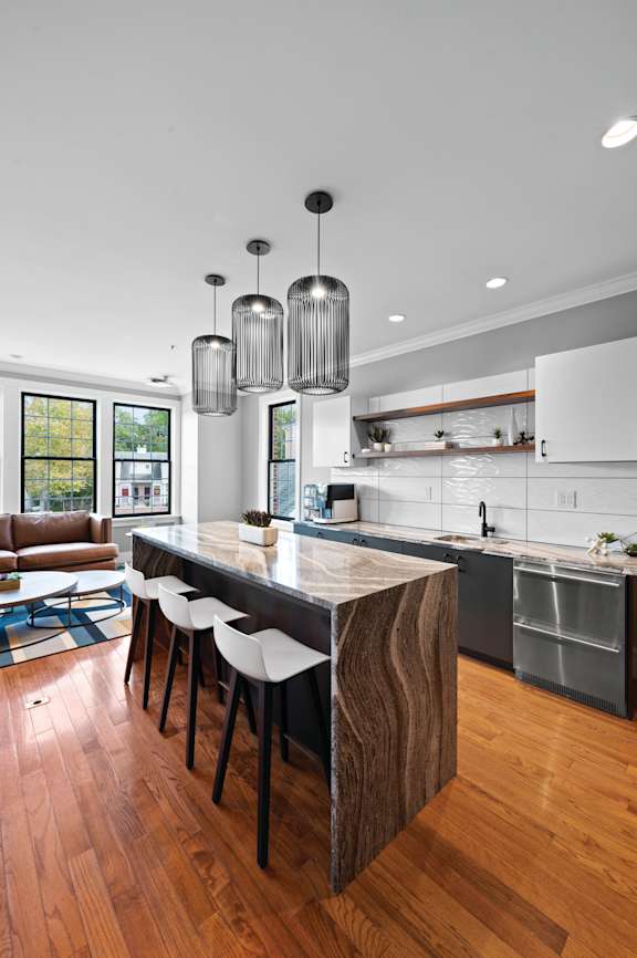 A kitchen with a wooden island and white stools.