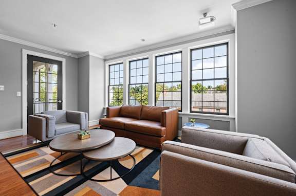 A living room with a brown leather couch and a round table.