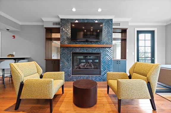 A living room with a fireplace and yellow chairs.