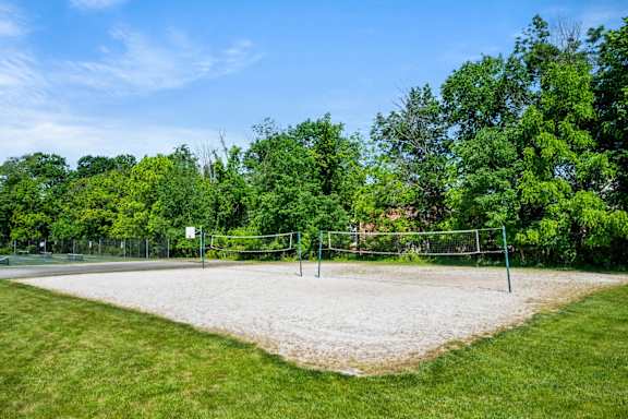 A sand volleyball court surrounded by trees.