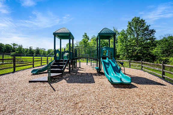 A playground with a green slide and a green and white structure.